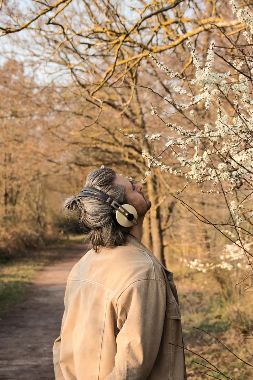 A neurodivergent adult pausing outdoors, wearing headphones.