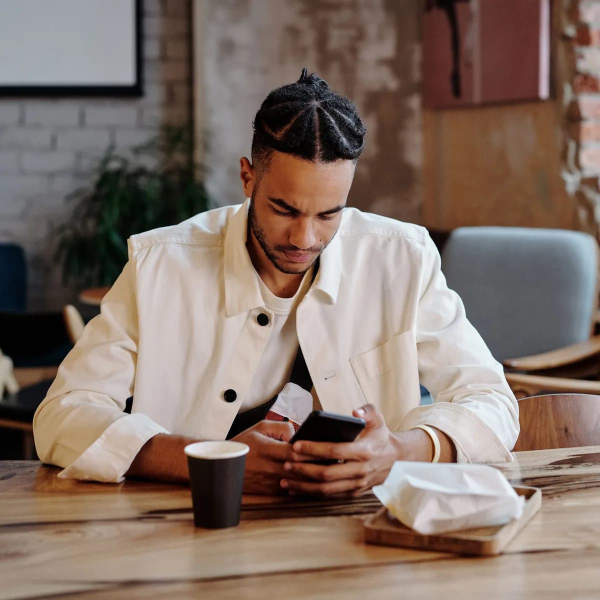 An adult in a cafe looking at their phone over a coffee.