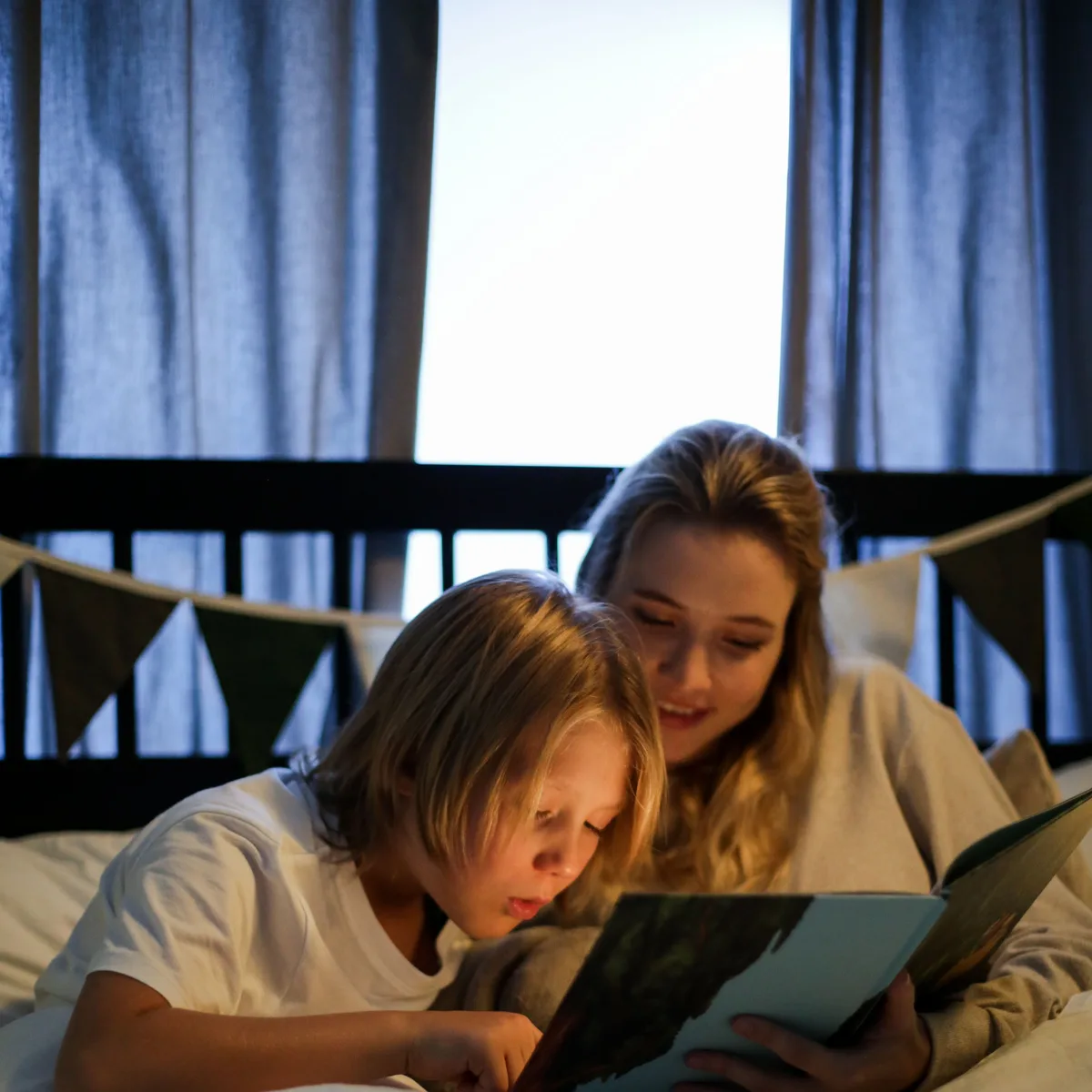 A parent and child reading a book together at bedtime.
